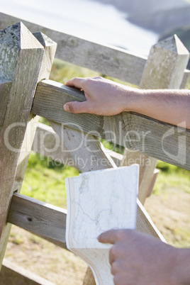 Man's hands on fence holding map