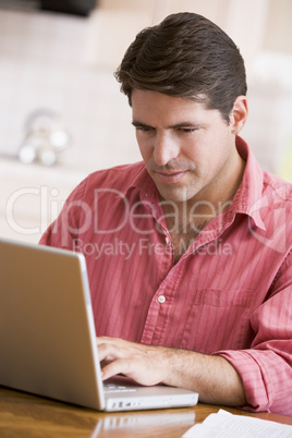 Man in kitchen using laptop