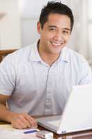 Man in dining room using laptop smiling