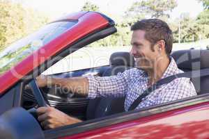 Man driving convertible car smiling