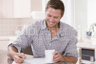 Man in kitchen reading newspaper and smiling