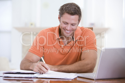 Man in dining room with laptop writing and smiling