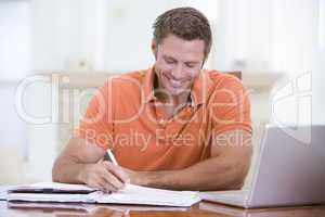 Man in dining room with laptop writing and smiling