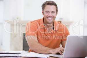 Man in dining room with laptop smiling