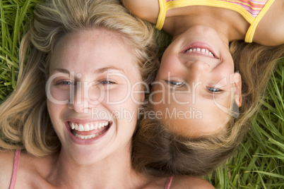 Woman and young girl lying in grass laughing