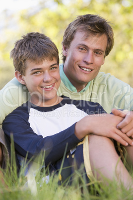 Man and young boy sitting outdoors smiling