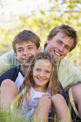 Man with two children sitting outdoors smiling Man with two children sitting outdoors smiling