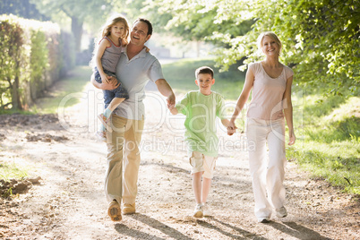 Family walking outdoors holding hands and smiling