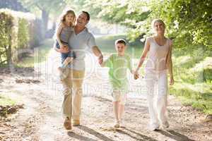 Family walking outdoors holding hands and smiling