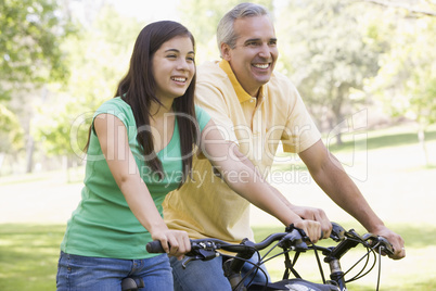 Man and girl on bikes outdoors smiling