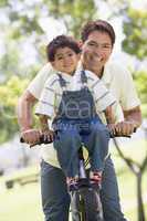 Man and young boy on a bike outdoors smiling