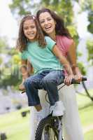 Woman and young girl on a bike outdoors smiling