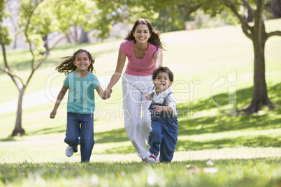 Woman with two young children running outdoors smiling