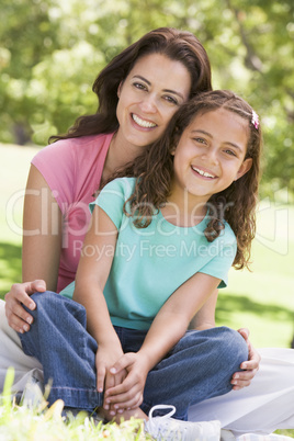 Woman and young girl sitting outdoors smiling