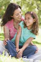 Woman and young girl sitting outdoors smiling