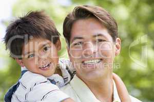 Man and young boy embracing outdoors smiling