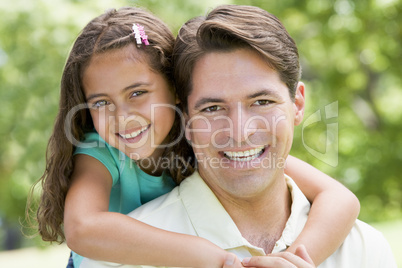 Man and young girl embracing outdoors smiling