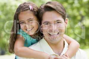 Man and young girl embracing outdoors smiling