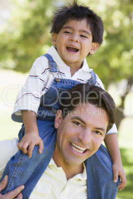 Man giving young boy shoulder ride outdoors smiling