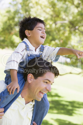 Man giving young boy shoulder ride outdoors smiling