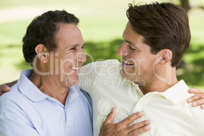 Two men standing outdoors bonding and smiling