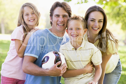 Family standing outdoors holding volleyball smiling