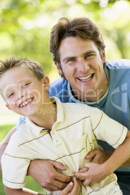 Man and young boy outdoors embracing and smiling Man and young boy outdoors embracing and smiling