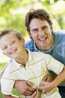 Man and young boy outdoors embracing and smiling