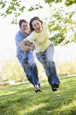 Couple running outdoors holding hands and smiling