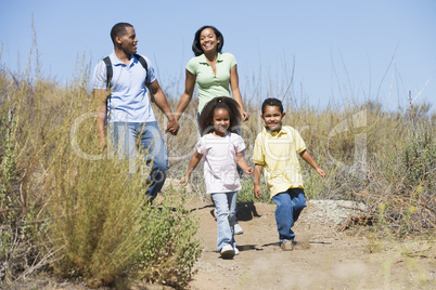 Family walking on path holding hands and smiling