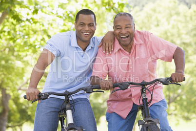 Two men on bikes outdoors smiling