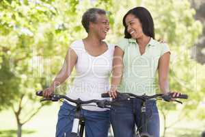 Two women on bikes outdoors smiling