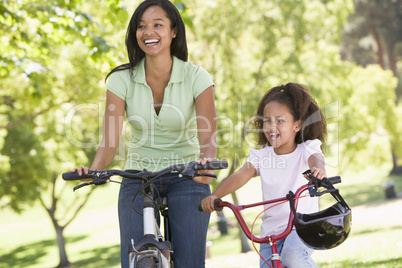 Woman and young girl on bikes outdoors smiling