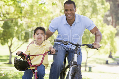 Man and young boy on bikes outdoors smiling