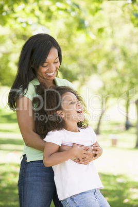 Woman and young girl outdoors embracing and smiling