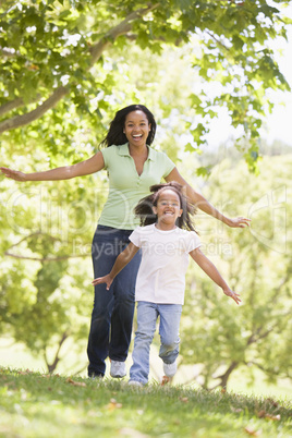 Woman and young girl running outdoors smiling