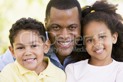 Man and two young children outdoors smiling