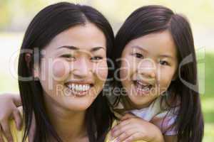 Woman and young girl outdoors embracing and smiling