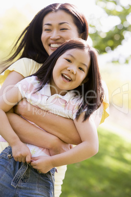 Woman and young girl outdoors embracing and smiling Woman and young girl outdoors embracing and smiling