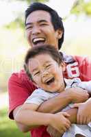 Man and young boy outdoors embracing and smiling