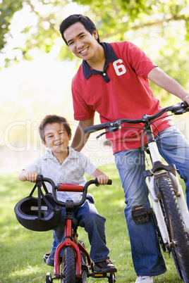 Man and young boy on bikes outdoors smiling