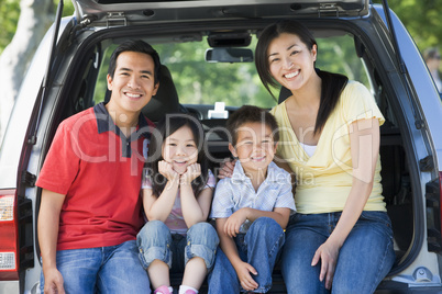 Family sitting in back of van smiling