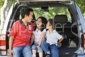Man with two children sitting in back of van smiling
