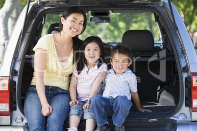 Woman with two children sitting in back of van smiling