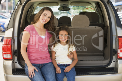 Woman with young girl sitting in back of van smiling