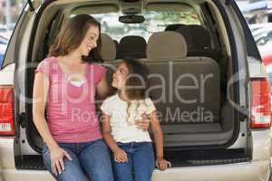 Woman with young girl sitting in back of van smiling