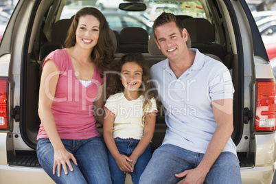 Family sitting in back of van smiling