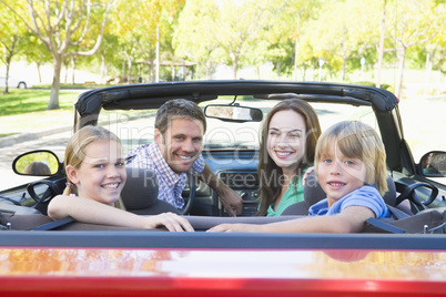 Family in convertible car smiling