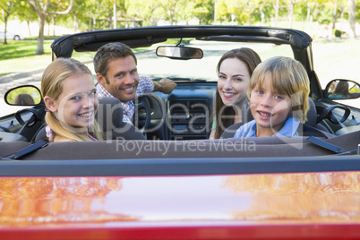 Family in convertible car smiling