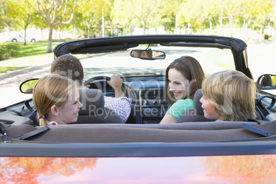 Family in convertible car smiling